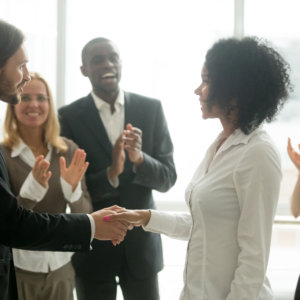 Grateful boss handshaking promoting african businesswoman congratulating with career achievement while colleagues applauding cheering successful worker, appreciation handshake, employee recognition